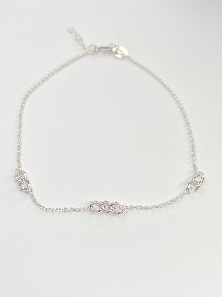 A delicate silver chain anklet with a alternative thicket link design with the cable link displayed on a clean white background.