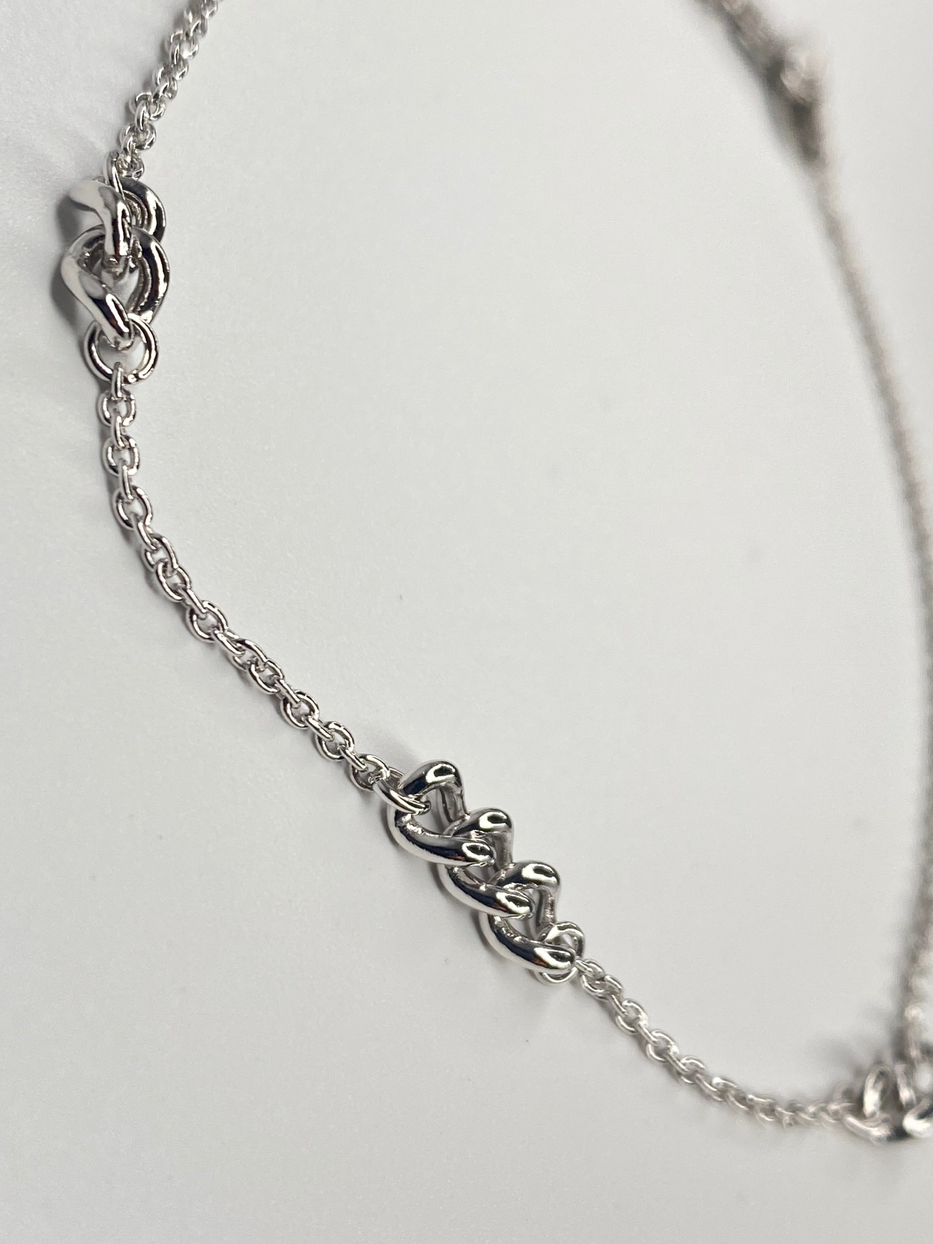 A silver chain anklet featuring three interlocking  link designs spaced along the chain, photographed on a plain light background.