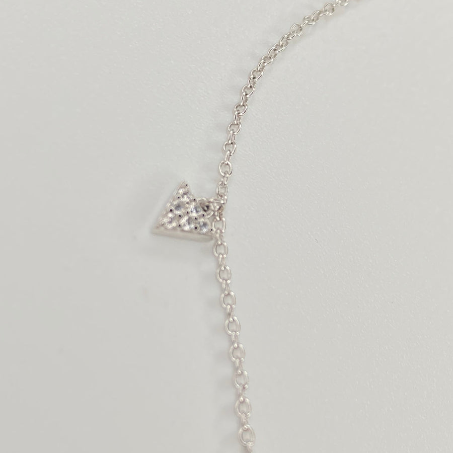 A delicate silver chain anklet featuring a small triangular pendant paved with clear cubic zirconias, displayed on a plain light gray background.