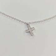 A delicate silver chain anklet with a small cross pendant adorned with clear cubic zirconias, displayed on a clean white background.