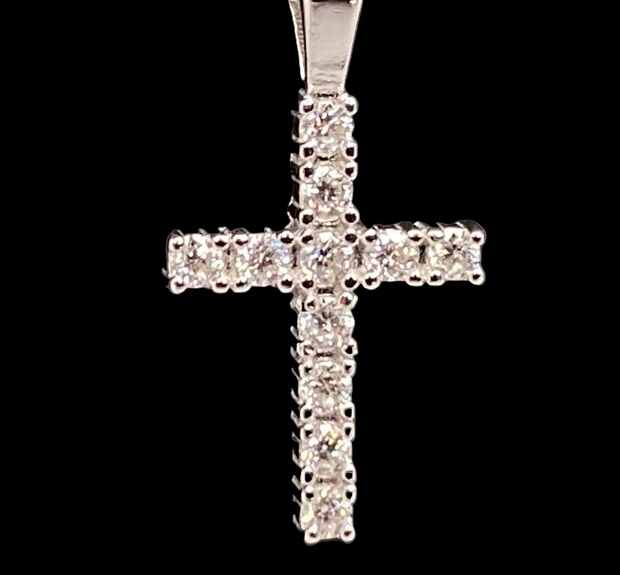 A silver cross pendant encrusted with clear moisanite  stones, displayed on a textured black background.