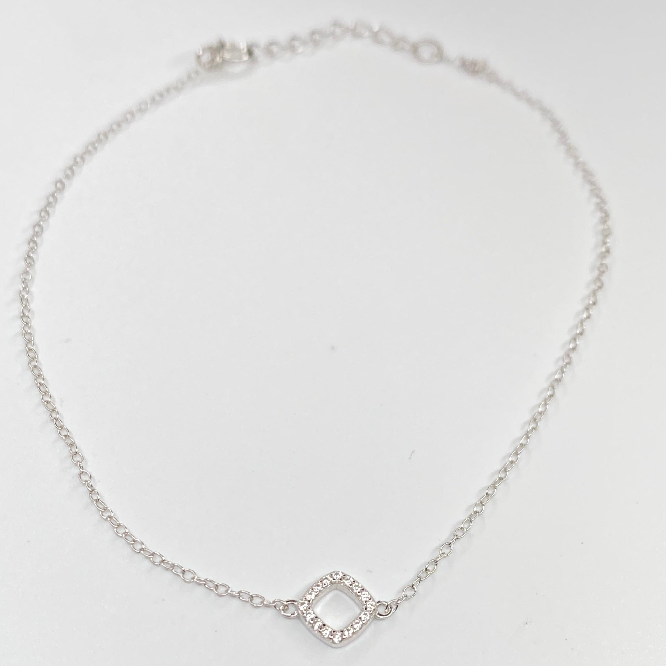 A delicate silver chain anklet featuring a small open diamond-shaped charm paved with tiny clear cubic zirconias, displayed on a clean white background.