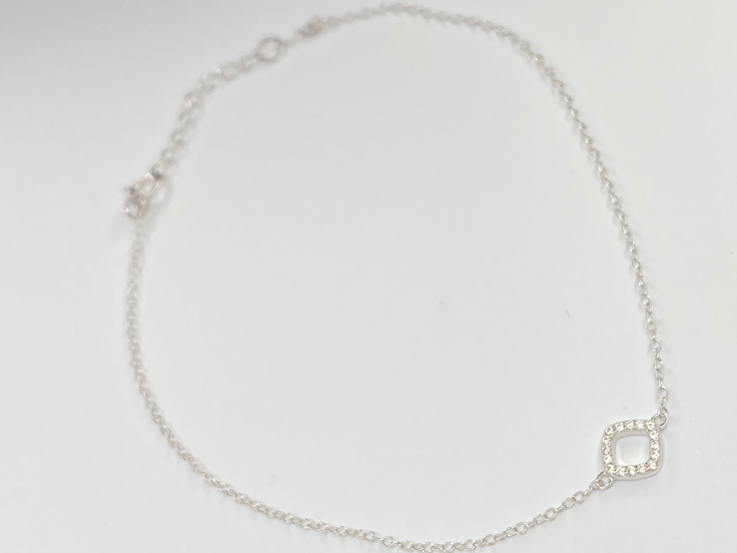 A delicate silver chain anklet with a small square link charm, displayed on a plain white background.