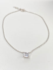 A delicate silver chain anklet with a single princess cut clear cz pendant in a prong setting, displayed on a plain white background.